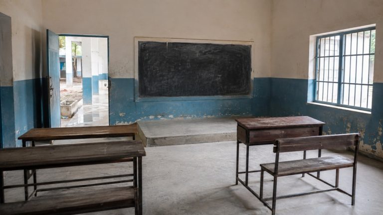 سرکاری اسکول کا کلاس روم جس میں خالی فرنیچر اور گندہ صحن دکھائی دے رہا ہے
