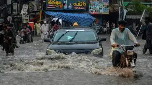 شدید بارش کے دوران نکاسی نہ ہونے کی وجہ سے سڑک پر کھڑا پانی اور متاثرہ عمارتیں