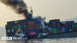 آب میں تیرتے کنٹینرز اور افراد سامان اکٹھا کرتے ہوئے